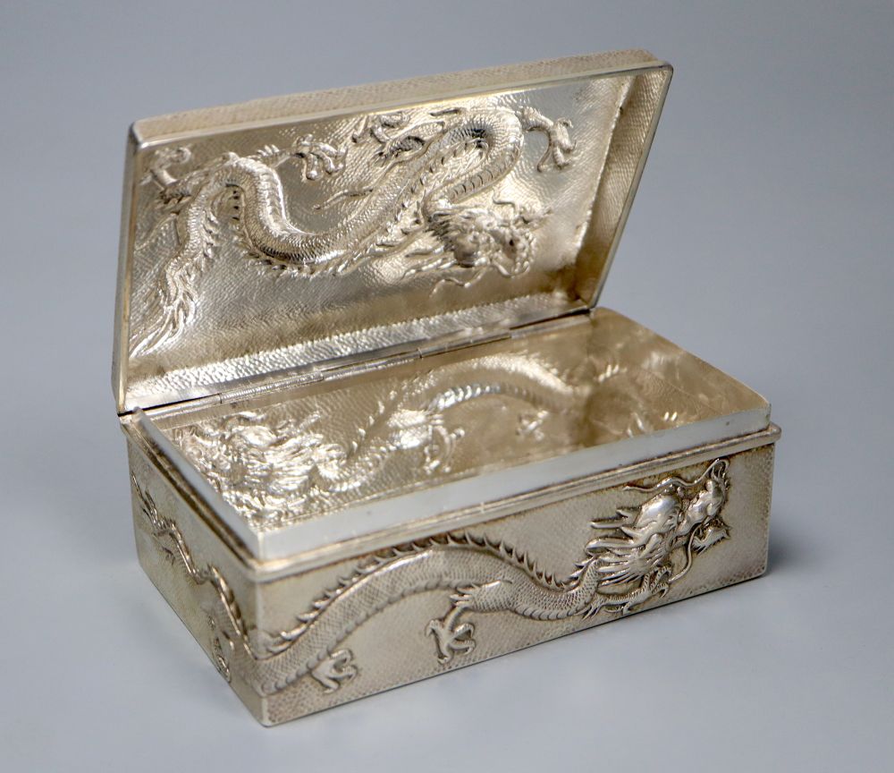 An early 20th century Chinese Export white metal cigarette box, embossed with a dragon, by Wang Hing, 13cm, gross 9oz.